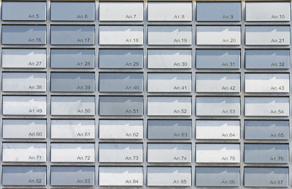 Rows of metallic apartment mailboxes organized in a neat, symmetrical grid pattern, creating a minimalist architectural design.
